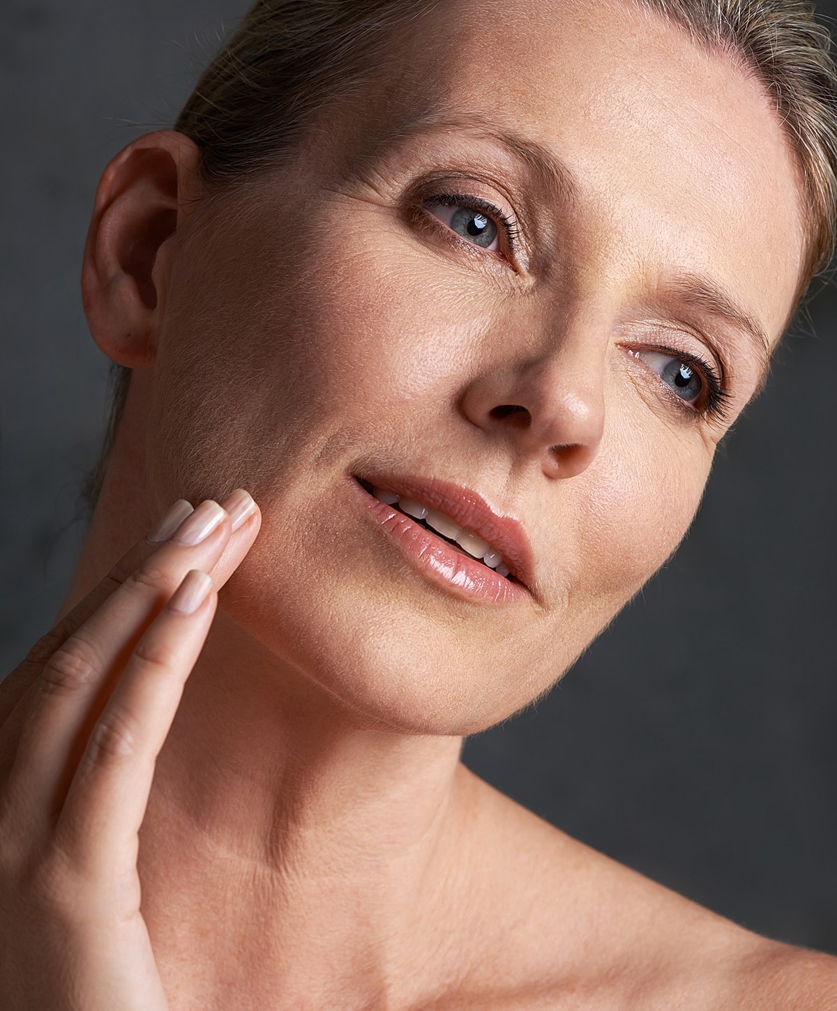 lower blepharoplasty patient model gently touching her face, natural beauty.