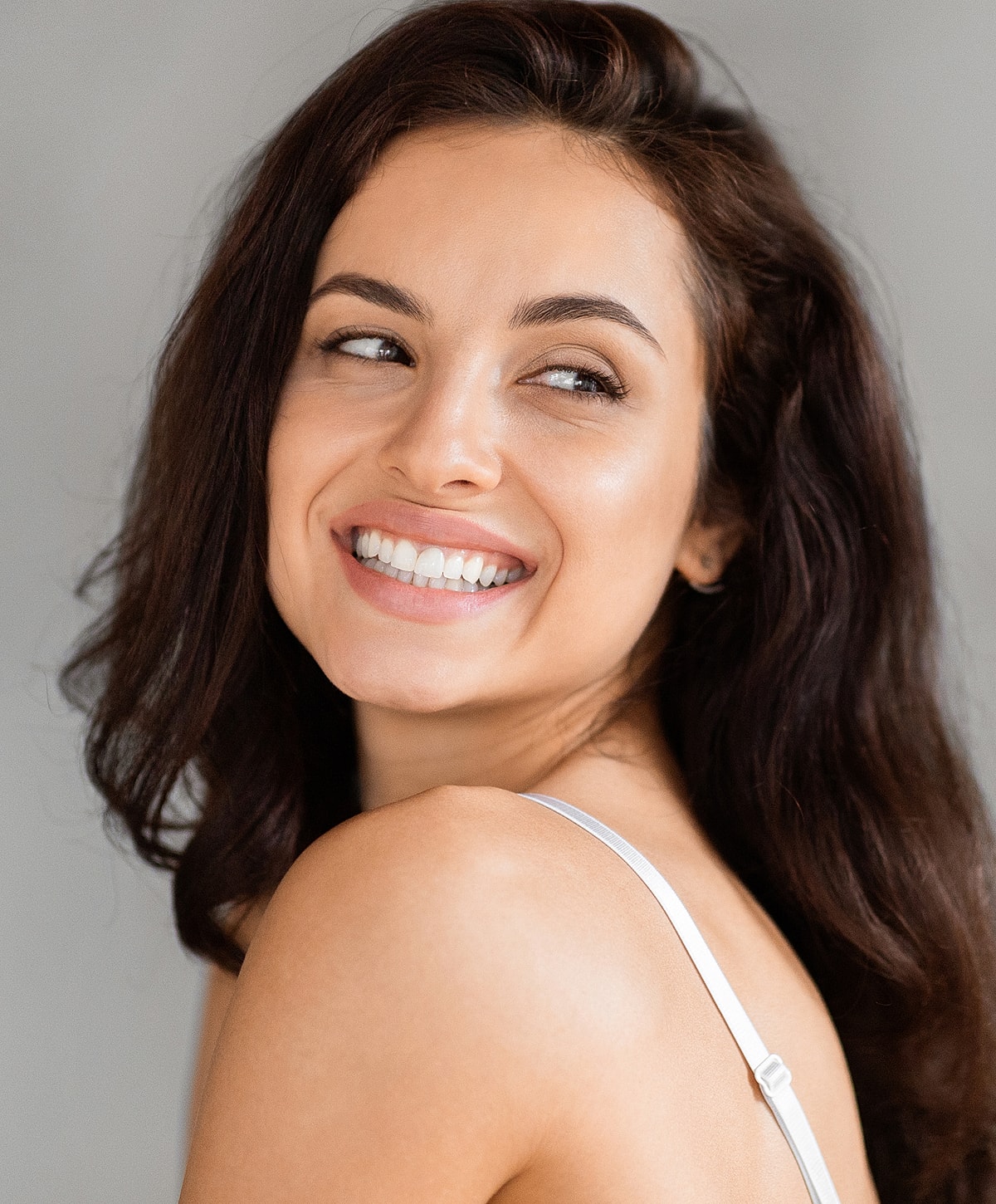 Smiling fat transfer patient model with long dark hair.
