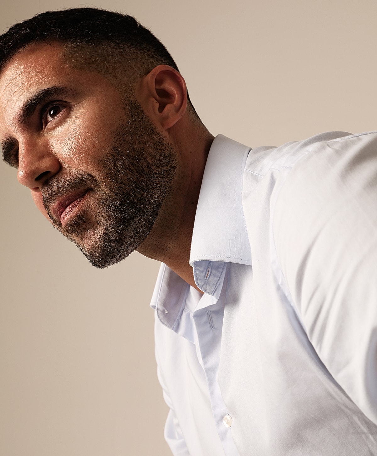 Male facelift patient model in a white shirt, looking thoughtfully ahead.
