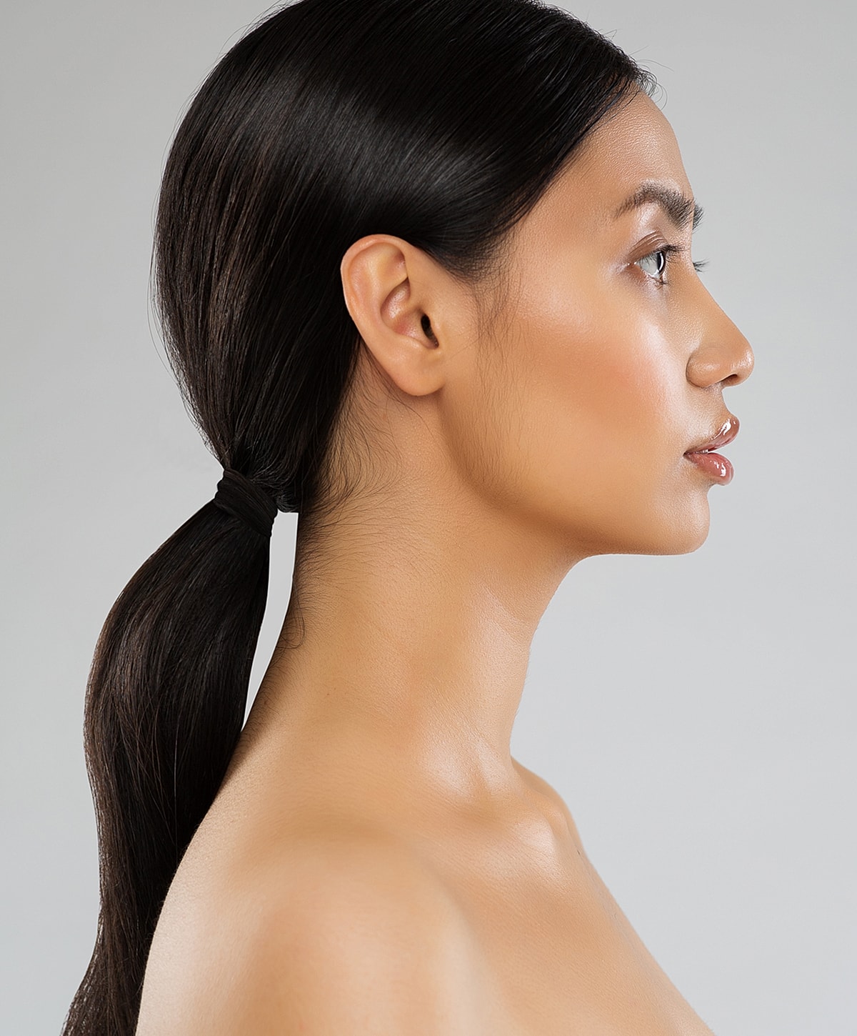 Profile portrait of a revision rhinoplasty patient model with sleek hair.