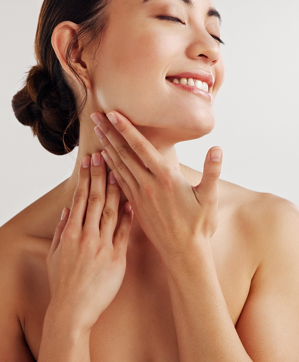 skin care patient model smiling, applying skincare to her face.