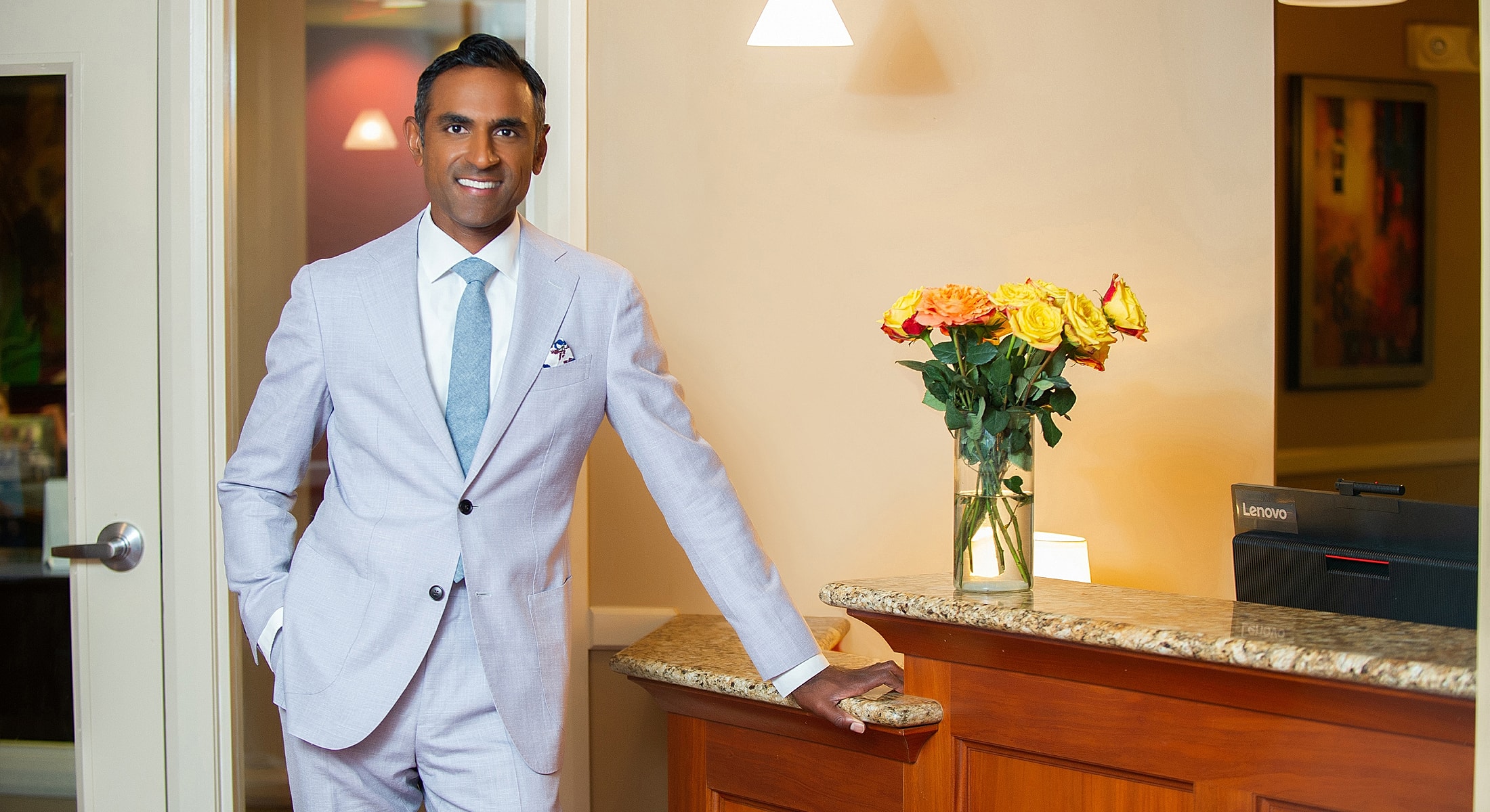 Man in suit at reception with flowers.
