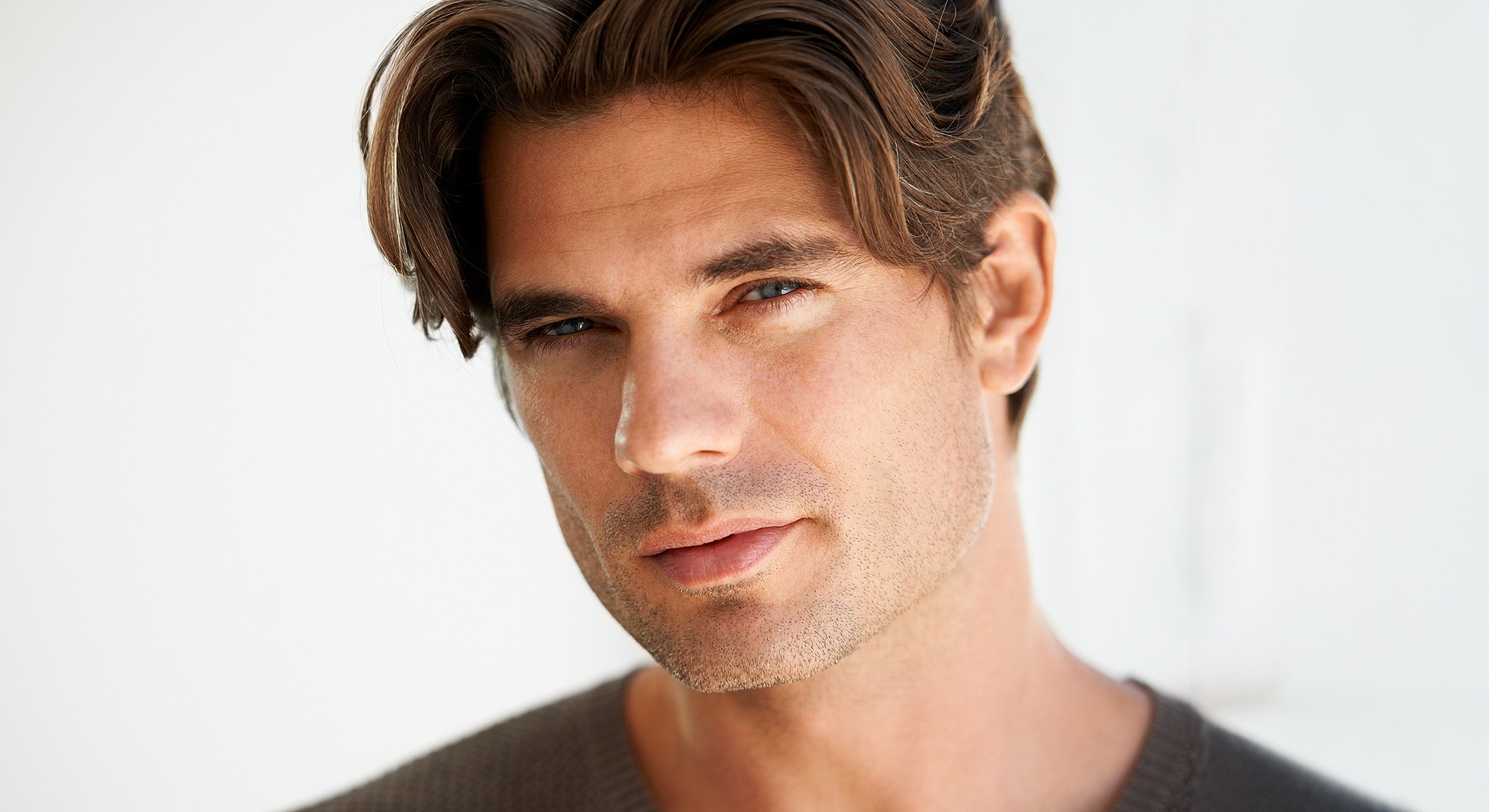 Close-up portrait of male facelift patient model with wavy hair.