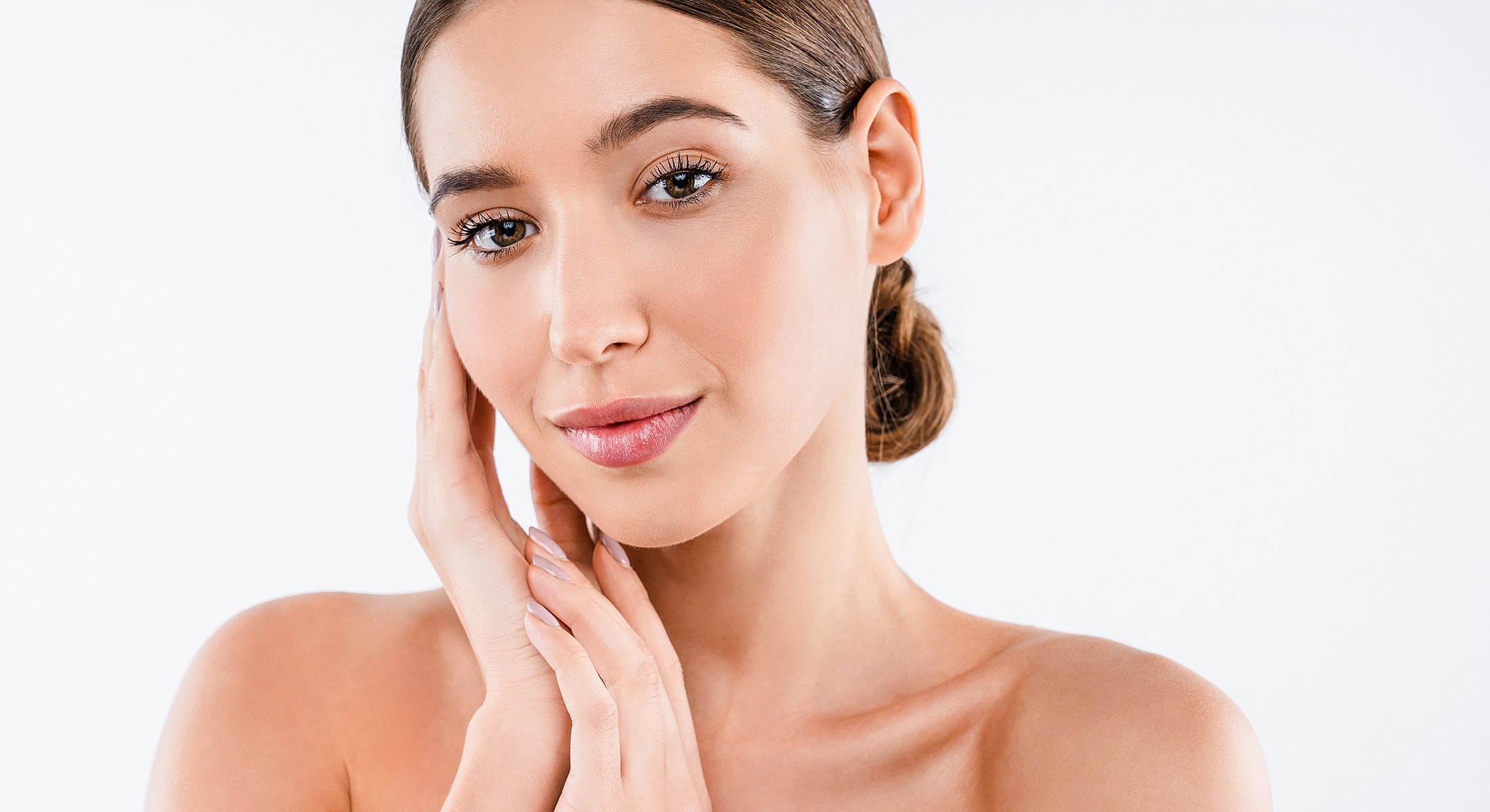 Smiling revision rhinoplasty patient model touching her face lightly.