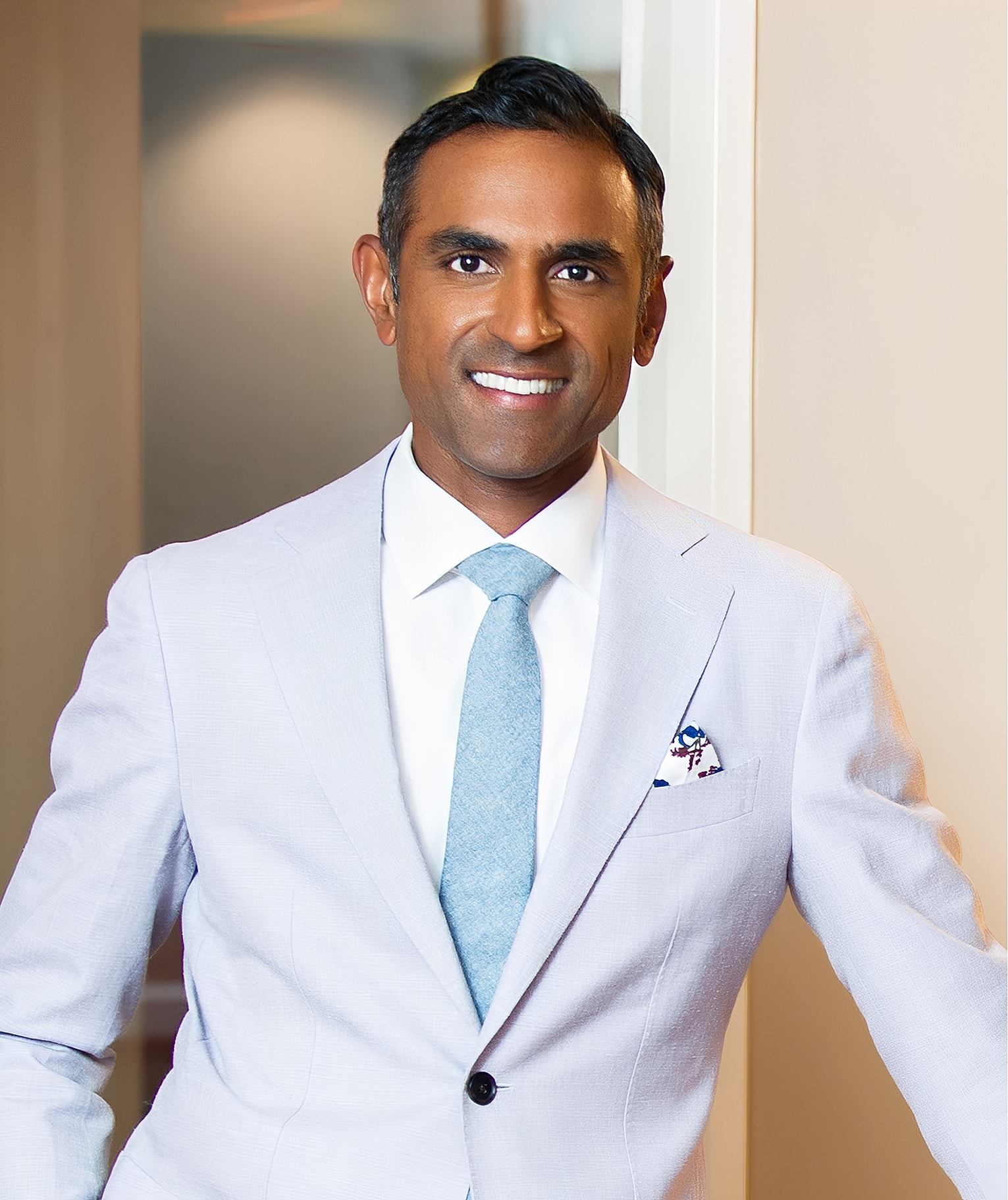 Smiling man in light suit and blue tie.